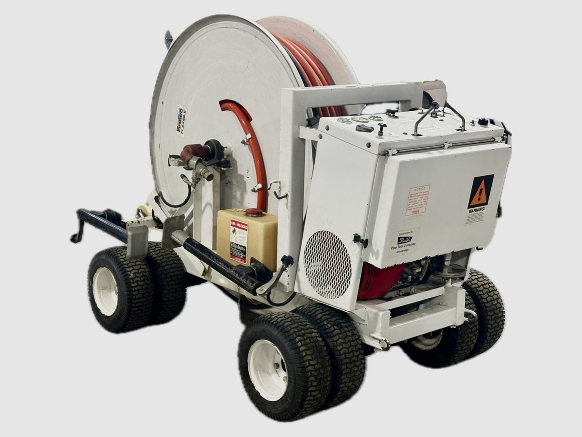 A four-wheeled easement machine with a large hose reel, jetting hose, gasoline engine and turf tires, photographed against a plain background